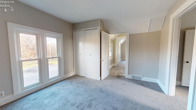 unfurnished bedroom with light carpet and a closet