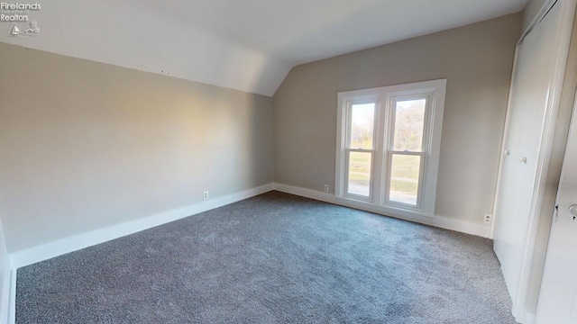 empty room with carpet flooring and vaulted ceiling