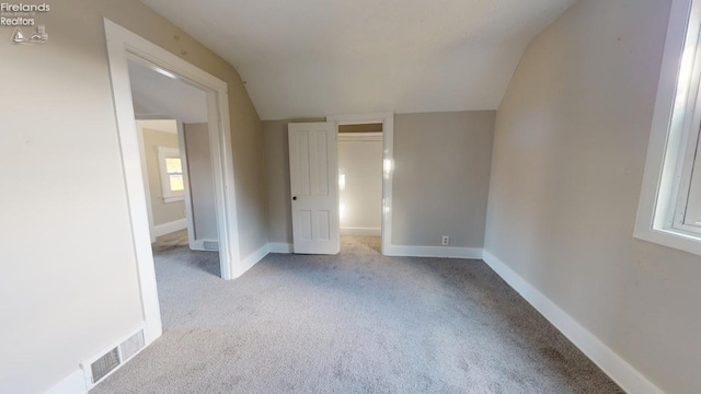 interior space with light colored carpet and lofted ceiling