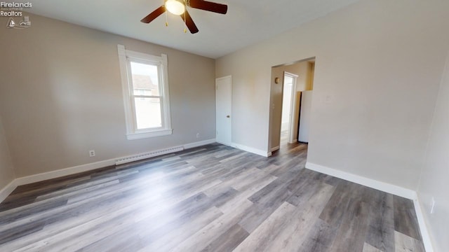 spare room with ceiling fan, hardwood / wood-style floors, and a baseboard heating unit