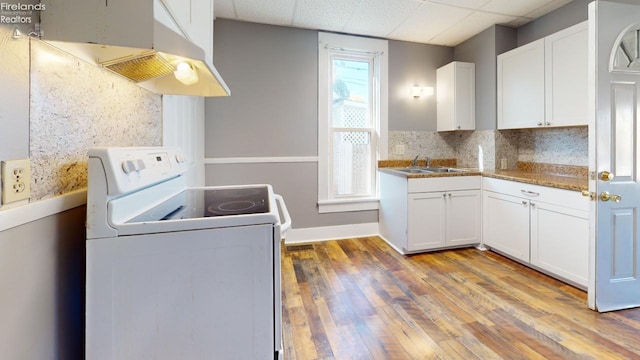 kitchen with white cabinetry, a drop ceiling, sink, electric stove, and light wood-type flooring