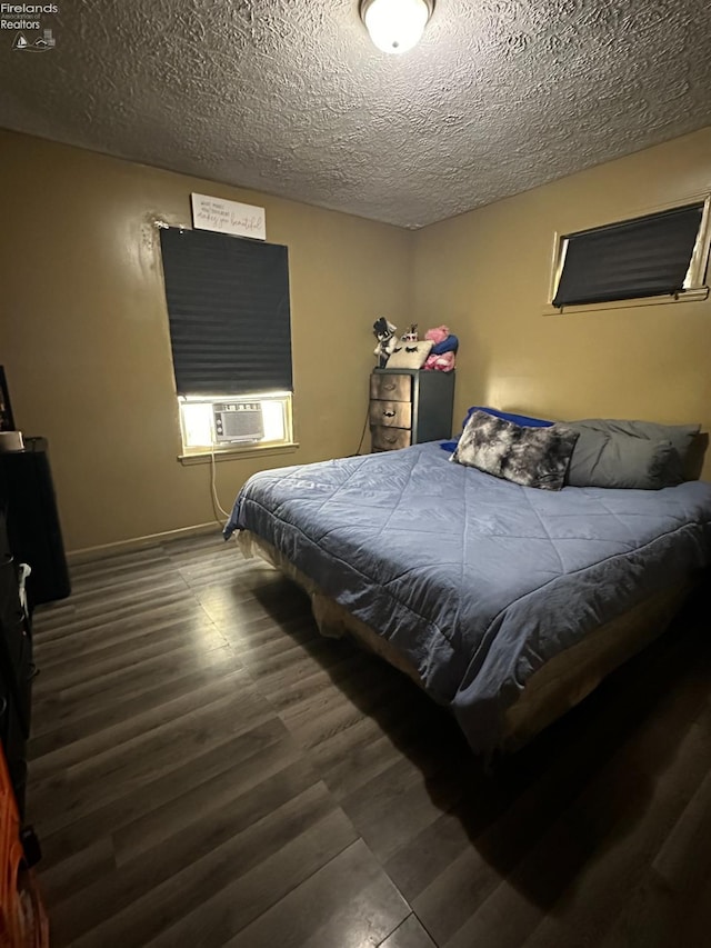 bedroom with cooling unit, dark hardwood / wood-style flooring, and a textured ceiling