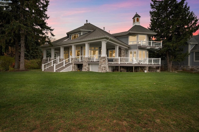 back house at dusk featuring a yard and a porch