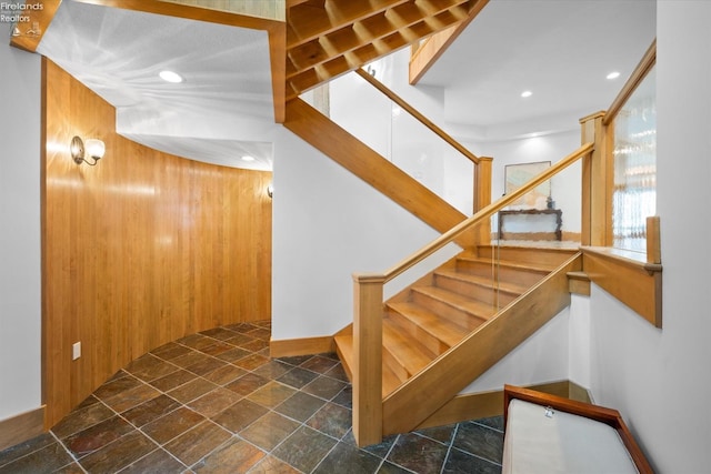 staircase featuring wood walls