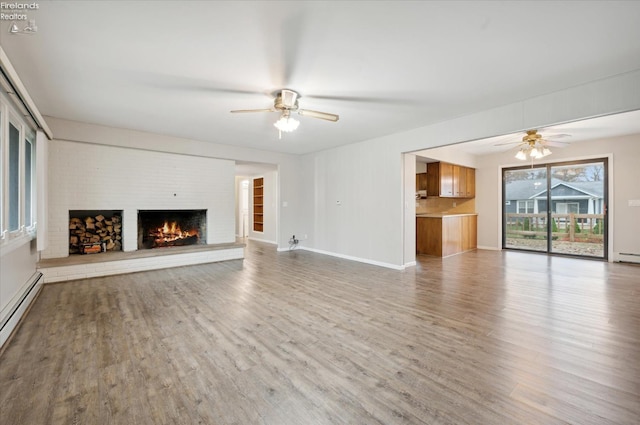 unfurnished living room featuring light wood-type flooring, a baseboard radiator, a brick fireplace, and ceiling fan