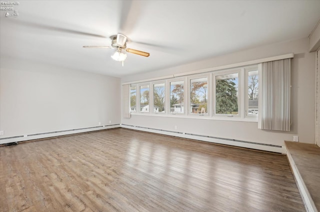 empty room featuring hardwood / wood-style flooring, ceiling fan, baseboard heating, and a wealth of natural light