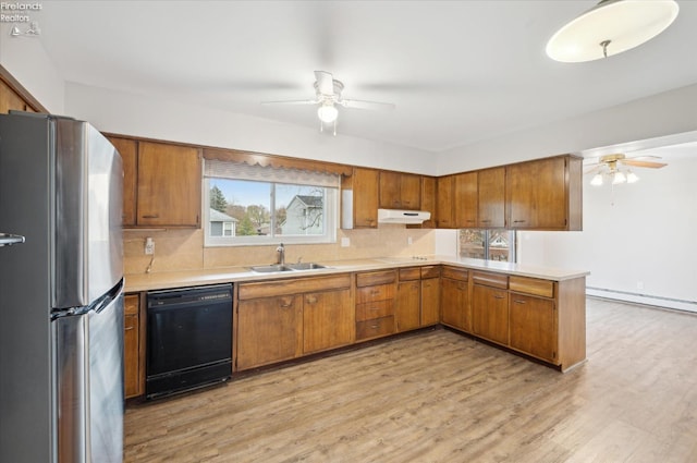 kitchen featuring a baseboard heating unit, sink, black dishwasher, light hardwood / wood-style floors, and stainless steel refrigerator