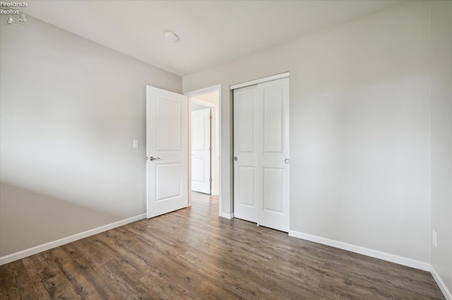 unfurnished bedroom featuring dark wood-type flooring and a closet