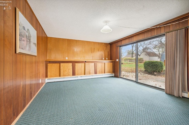 unfurnished room with wooden walls, carpet floors, a textured ceiling, and a baseboard heating unit