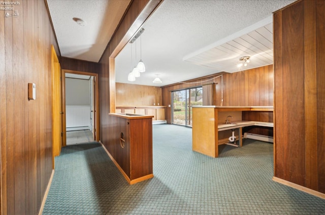 kitchen with pendant lighting, kitchen peninsula, wooden walls, and dark colored carpet