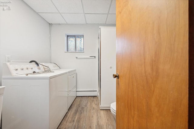 washroom with washer and clothes dryer, baseboard heating, and light hardwood / wood-style flooring