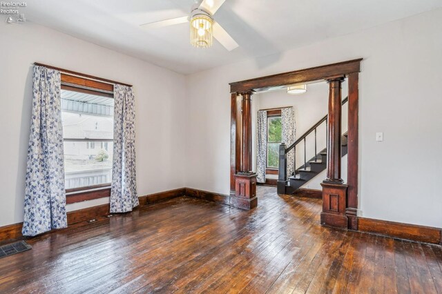 spare room with dark hardwood / wood-style flooring, decorative columns, and ceiling fan