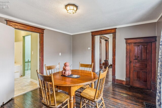 dining area featuring a textured ceiling, crown molding, and dark wood-type flooring