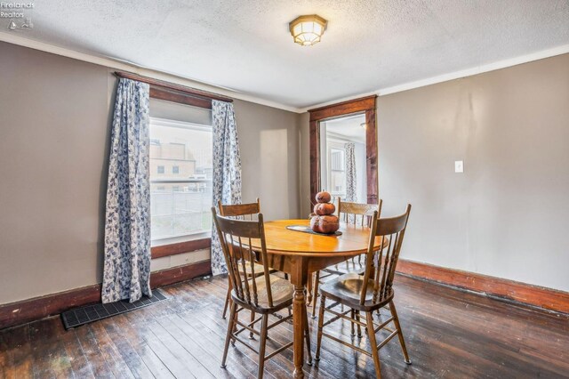 dining area featuring ornamental molding, a textured ceiling, and dark wood-type flooring