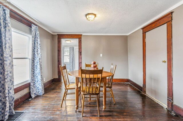 dining space with a textured ceiling, dark hardwood / wood-style flooring, and ornamental molding