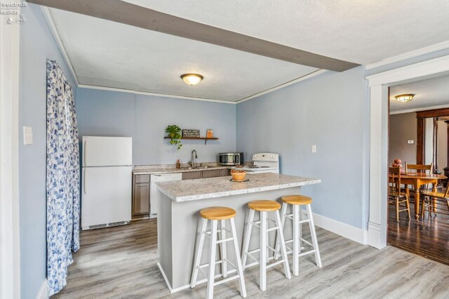 kitchen with a kitchen breakfast bar, light hardwood / wood-style flooring, white appliances, and sink