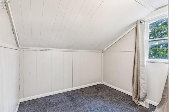 bonus room with wood walls, carpet floors, and lofted ceiling