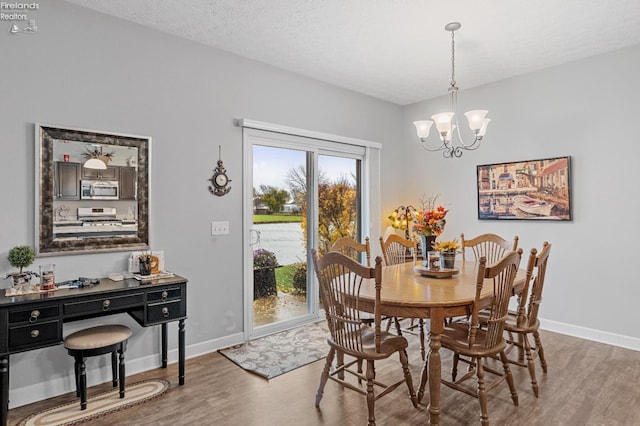 dining space with a textured ceiling, hardwood / wood-style flooring, and an inviting chandelier