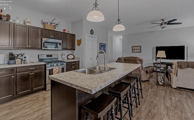 kitchen with stainless steel appliances, sink, hanging light fixtures, a breakfast bar area, and an island with sink