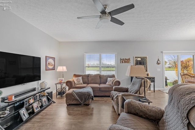 living room with hardwood / wood-style flooring, a water view, a textured ceiling, and a wealth of natural light