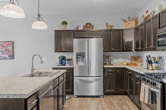 2133 S Harbor Bay Dr, Marblehead, OH 43440 - kitchen with stainless steel appliances, a sink, a textured ceiling, light wood-style flooring, and dark brown cabinets