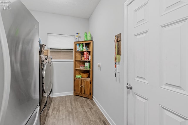 laundry room with washer and clothes dryer, a textured ceiling, and light wood-type flooring