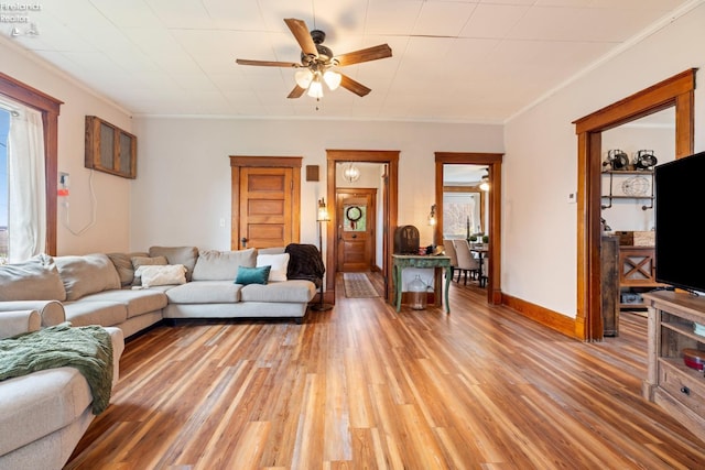 living room with light wood-type flooring, ceiling fan, and crown molding