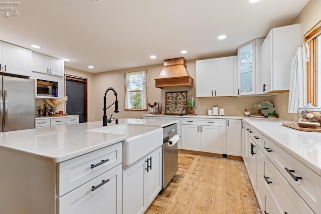 kitchen with white cabinets, custom exhaust hood, and an island with sink