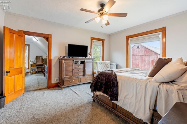 carpeted bedroom with radiator heating unit, vaulted ceiling, ceiling fan, and crown molding