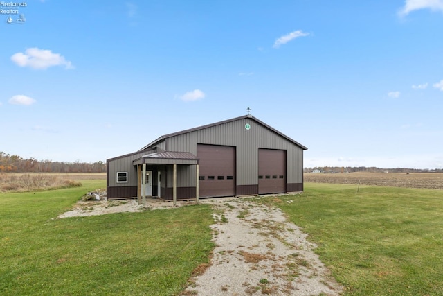 view of outbuilding with a rural view, a garage, and a lawn