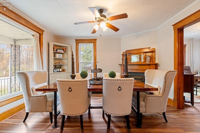 dining area with built in shelves, hardwood / wood-style floors, ceiling fan, and ornamental molding