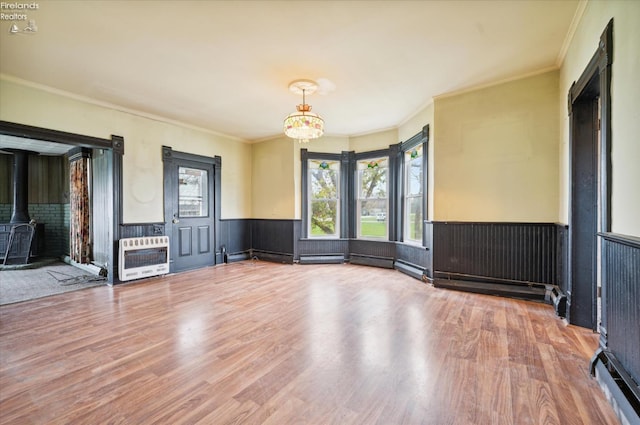 spare room featuring heating unit, a wealth of natural light, crown molding, and hardwood / wood-style flooring