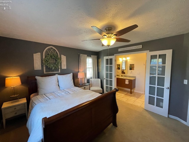 bedroom featuring a textured ceiling, light colored carpet, ensuite bath, and ceiling fan