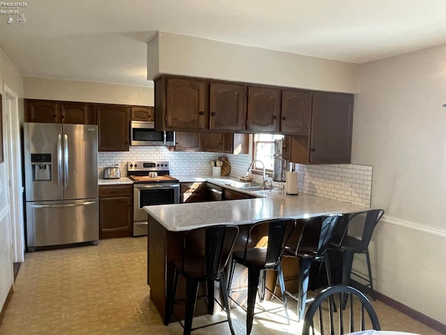 kitchen featuring kitchen peninsula, sink, a breakfast bar, and appliances with stainless steel finishes