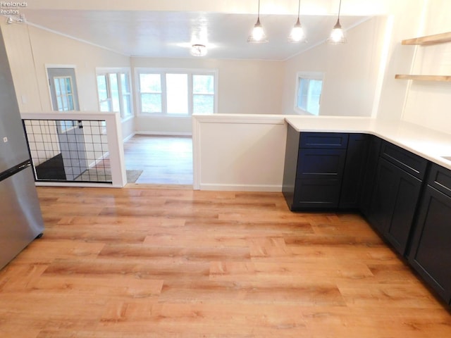 kitchen featuring decorative light fixtures, light wood-type flooring, crown molding, and stainless steel refrigerator