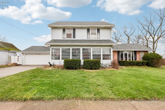 view of property with a sunroom, a garage, and a front yard