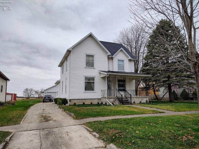 view of front facade with an outbuilding, a garage, a front lawn, and covered porch