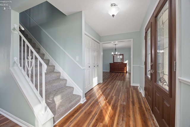 foyer entrance with an inviting chandelier and dark wood-type flooring