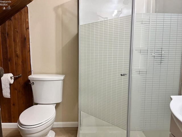 bathroom with vanity, toilet, an enclosed shower, and wooden walls