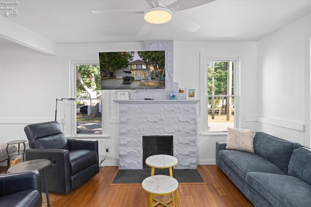 living room featuring a fireplace, wood-type flooring, and ceiling fan