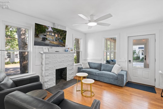 living room featuring a fireplace, wood-type flooring, ceiling fan, and a healthy amount of sunlight