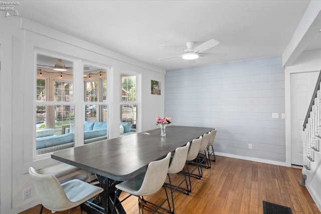 dining space featuring hardwood / wood-style floors, ceiling fan, and wood walls