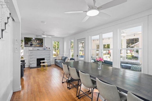 dining space with ceiling fan, wood-type flooring, and a fireplace