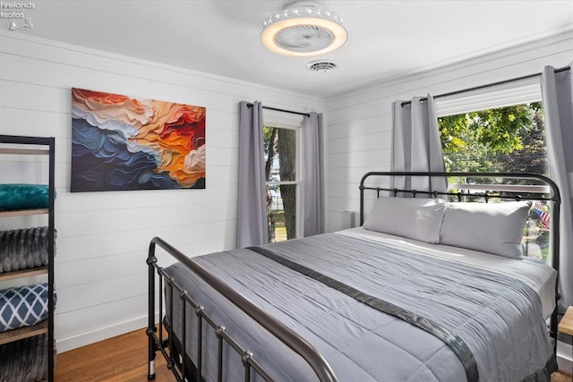 bedroom featuring wood-type flooring, multiple windows, and wood walls