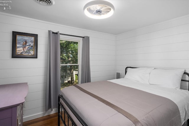 bedroom with dark hardwood / wood-style floors and wooden walls