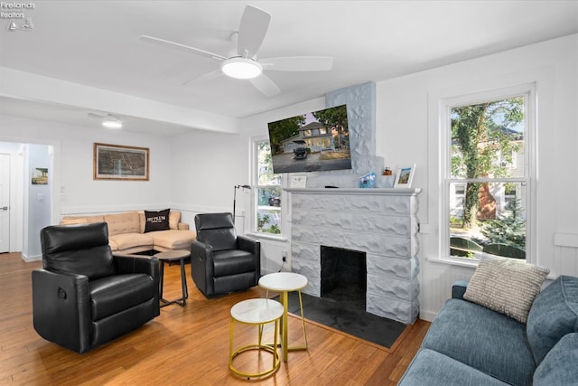 living room with a fireplace, ceiling fan, plenty of natural light, and hardwood / wood-style flooring