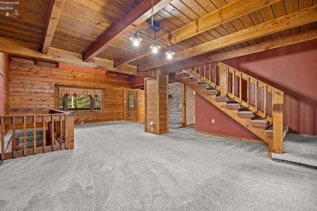 unfurnished living room with beam ceiling, wood walls, carpet floors, and wood ceiling