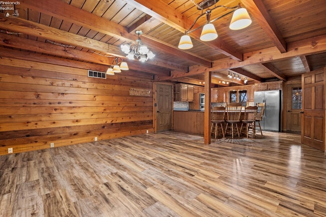 unfurnished living room featuring beam ceiling, hardwood / wood-style flooring, wooden walls, and wood ceiling