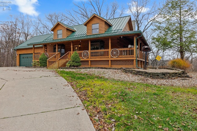 log cabin featuring covered porch and a garage