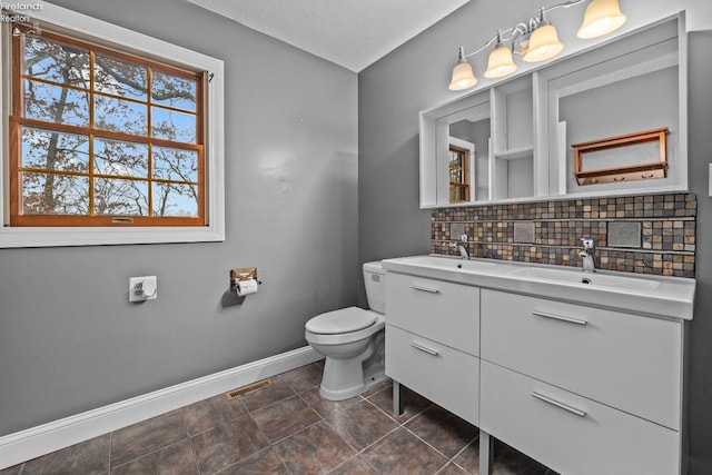 bathroom featuring tasteful backsplash, tile patterned flooring, vanity, and toilet